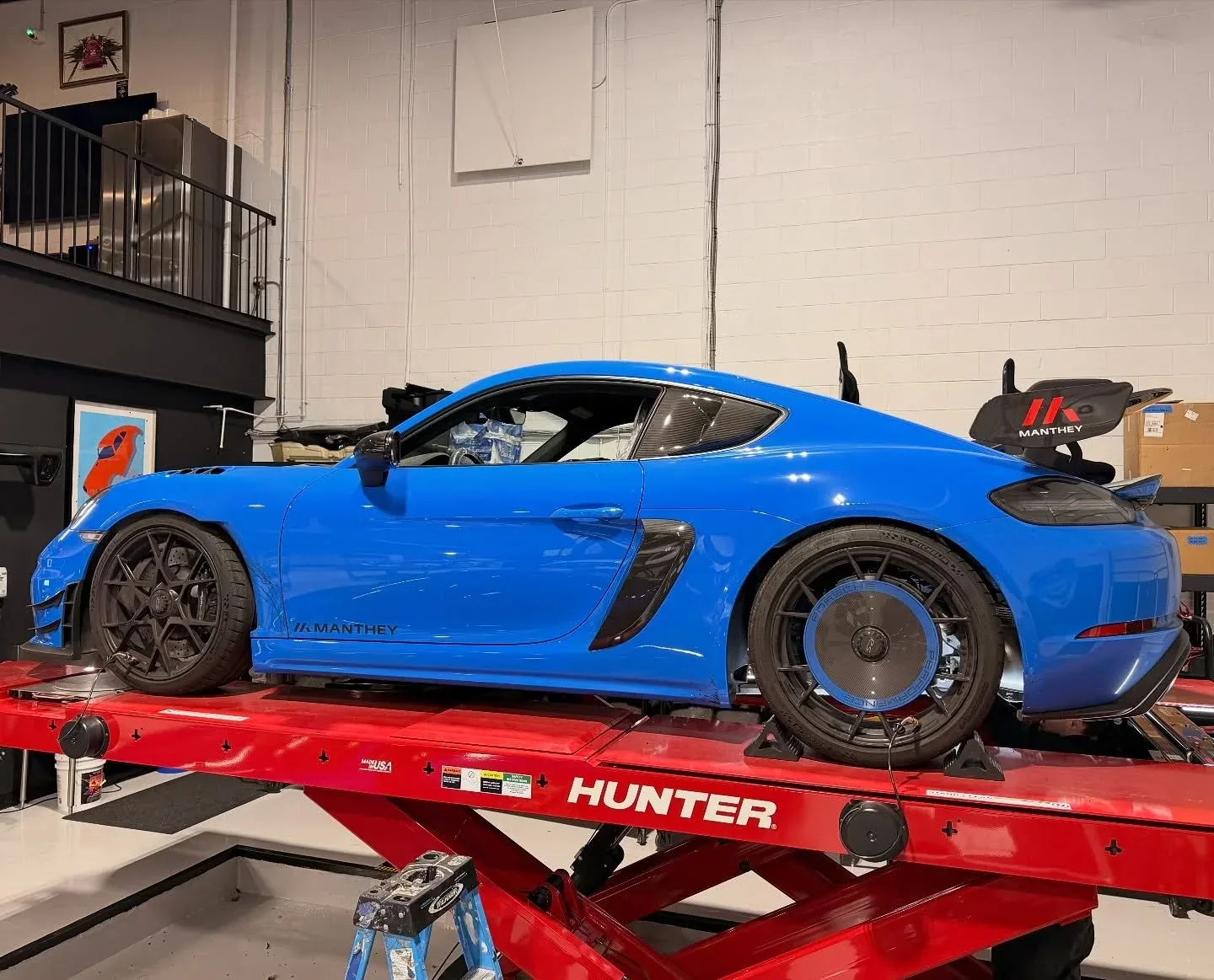 A Shark Blue Porsche 718 Cayman GT4 RS with Manthey aerodynamics on the lift
